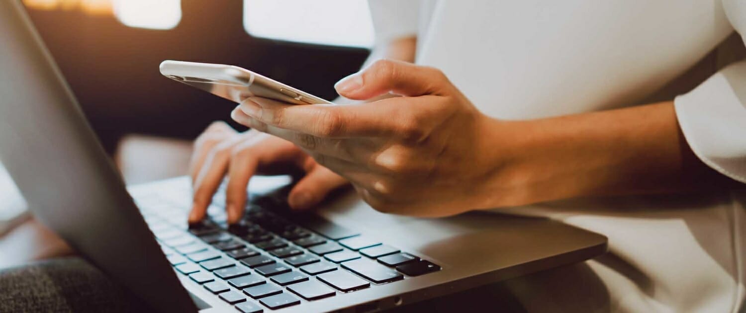 Close up view of person on their phone and laptop