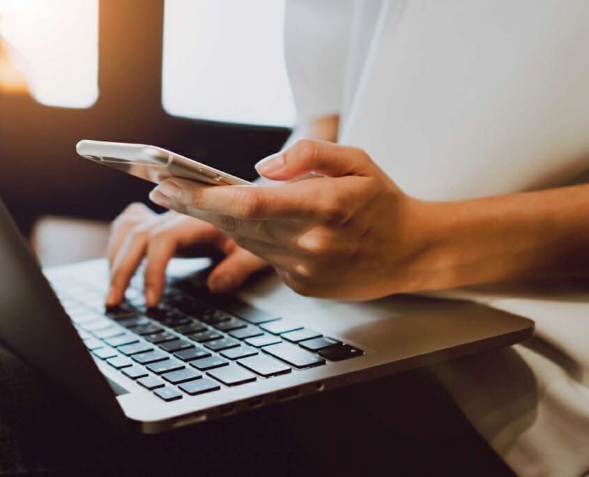 Close up view of person on their phone and laptop