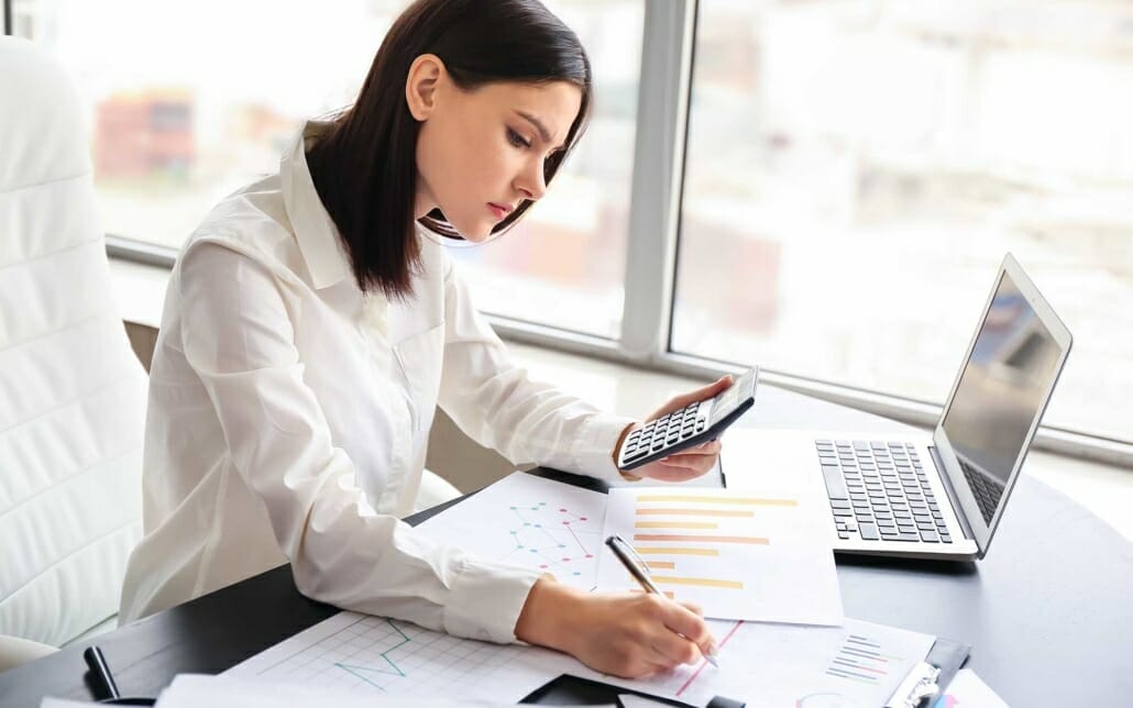 View of woman working on a computer with calculator