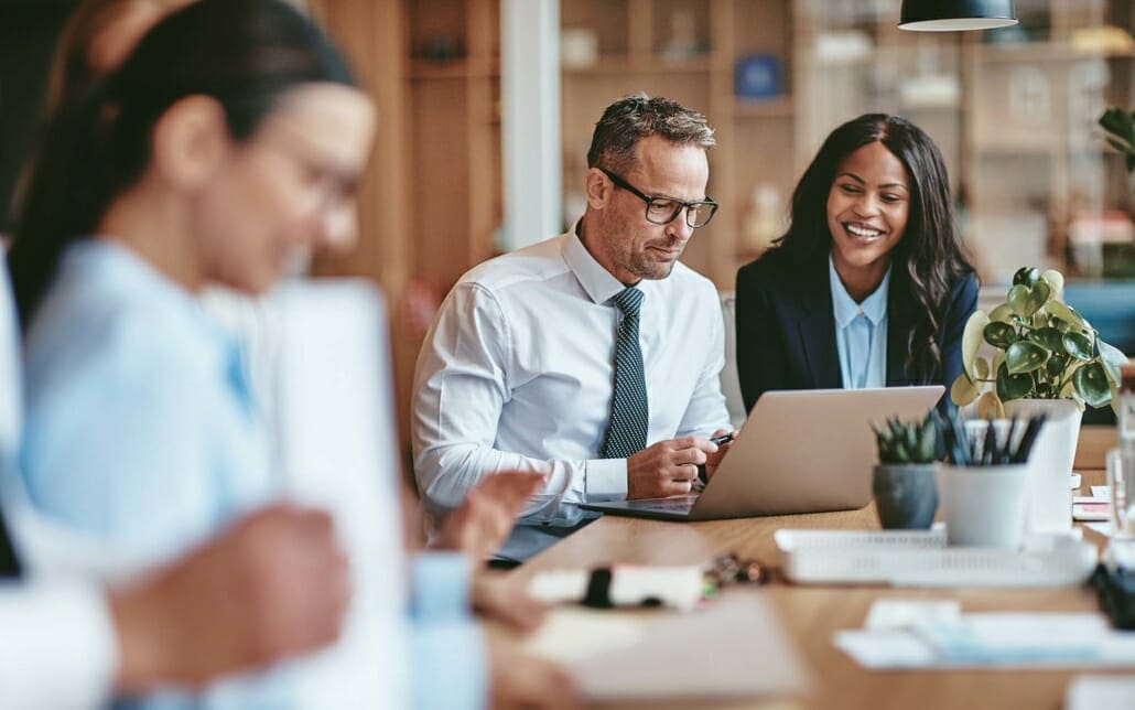 View of two office workers looking at a laptop